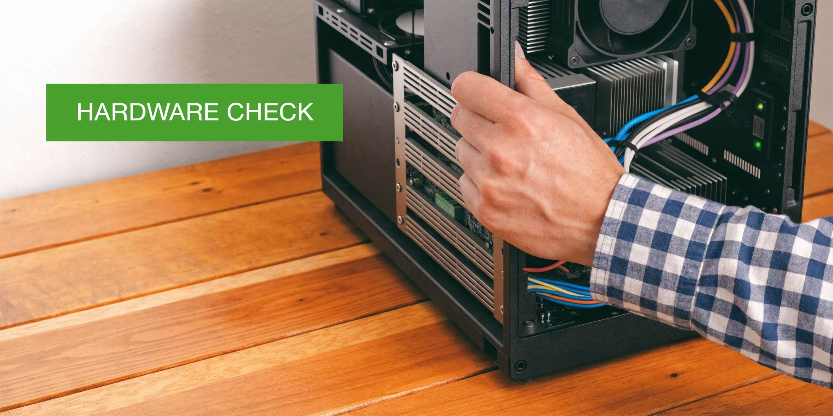 A person checking the hardware components inside a computer case while placed on a wooden table.