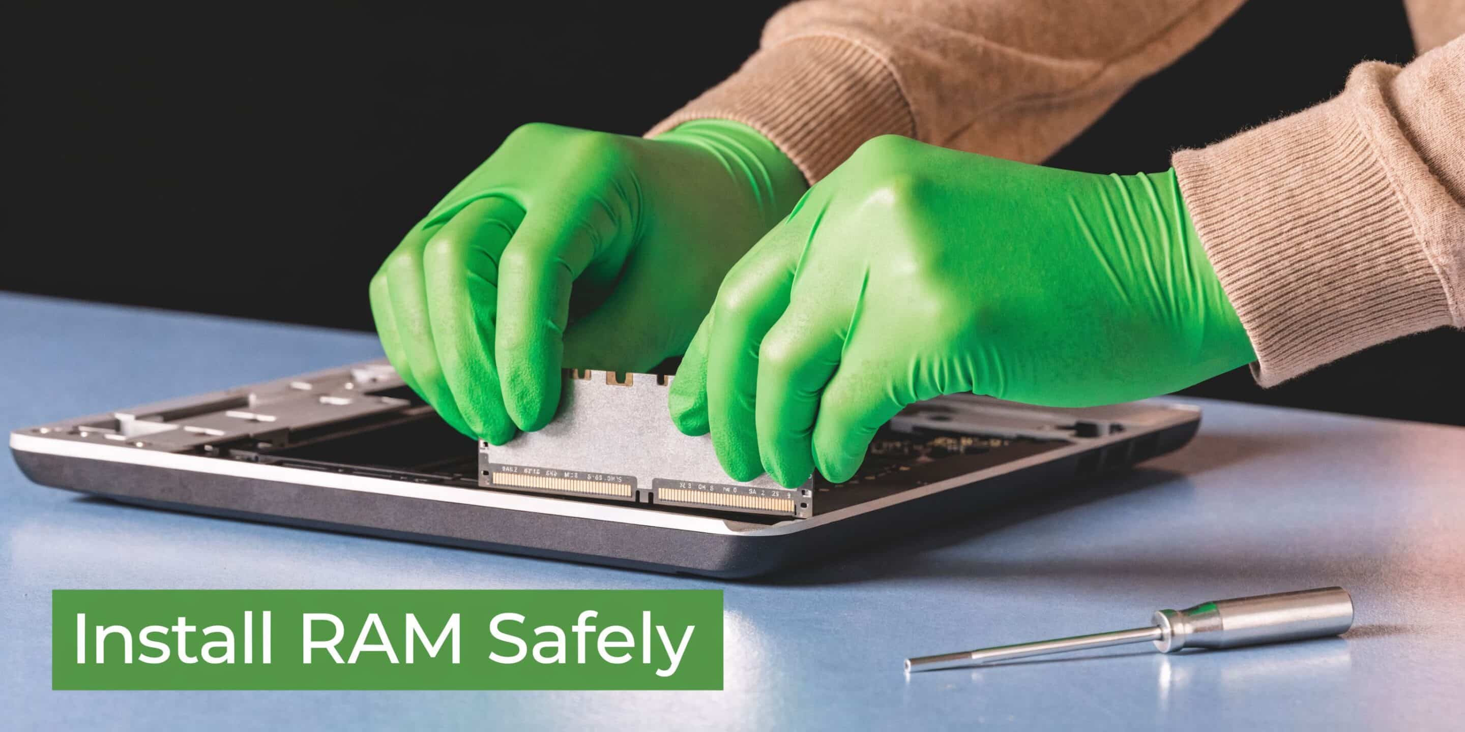 A technician wearing green gloves carefully installing a RAM module into a laptop computer on a desk.