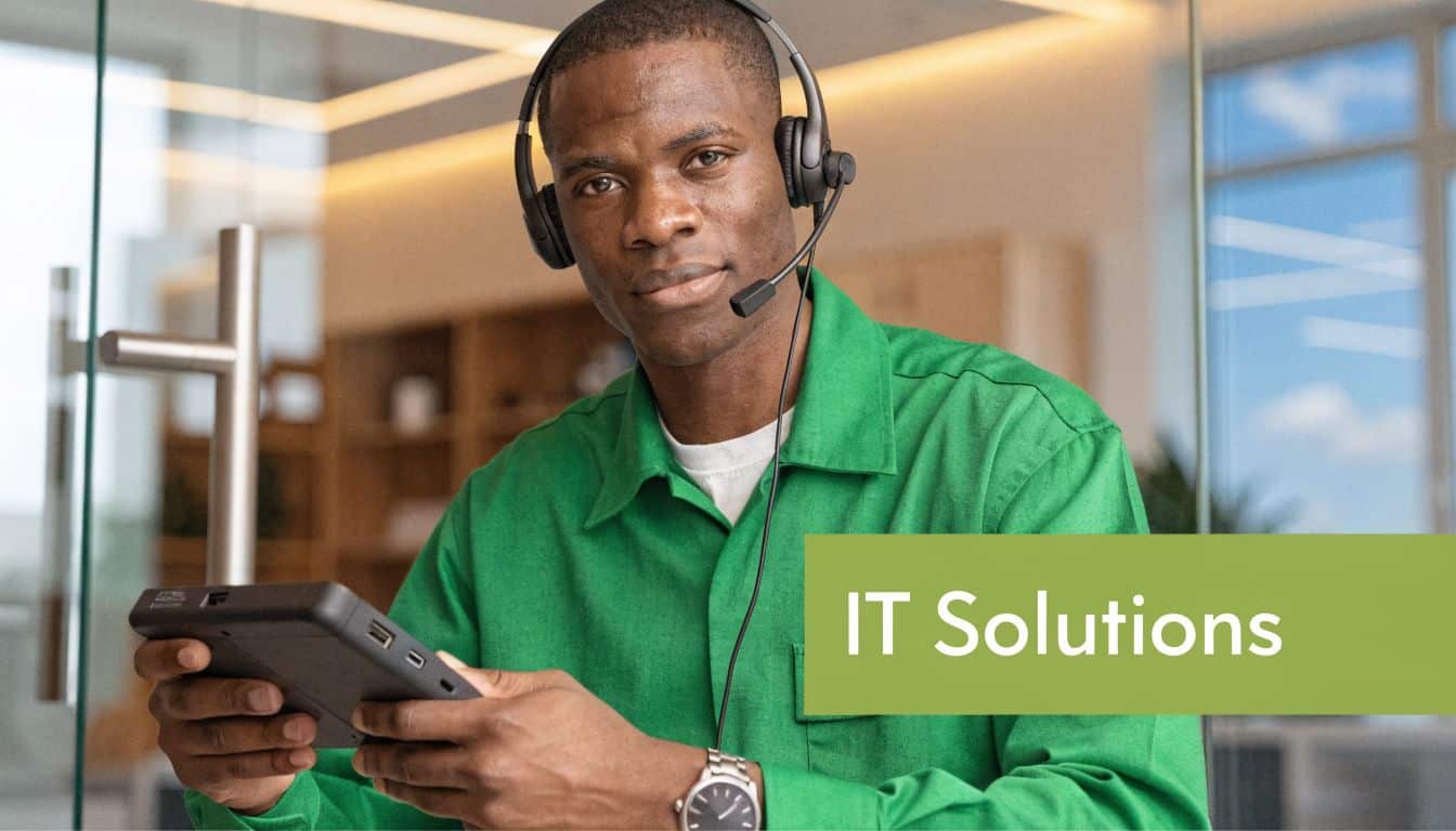An IT support technician wearing a headset while holding a small electronic device in an office.