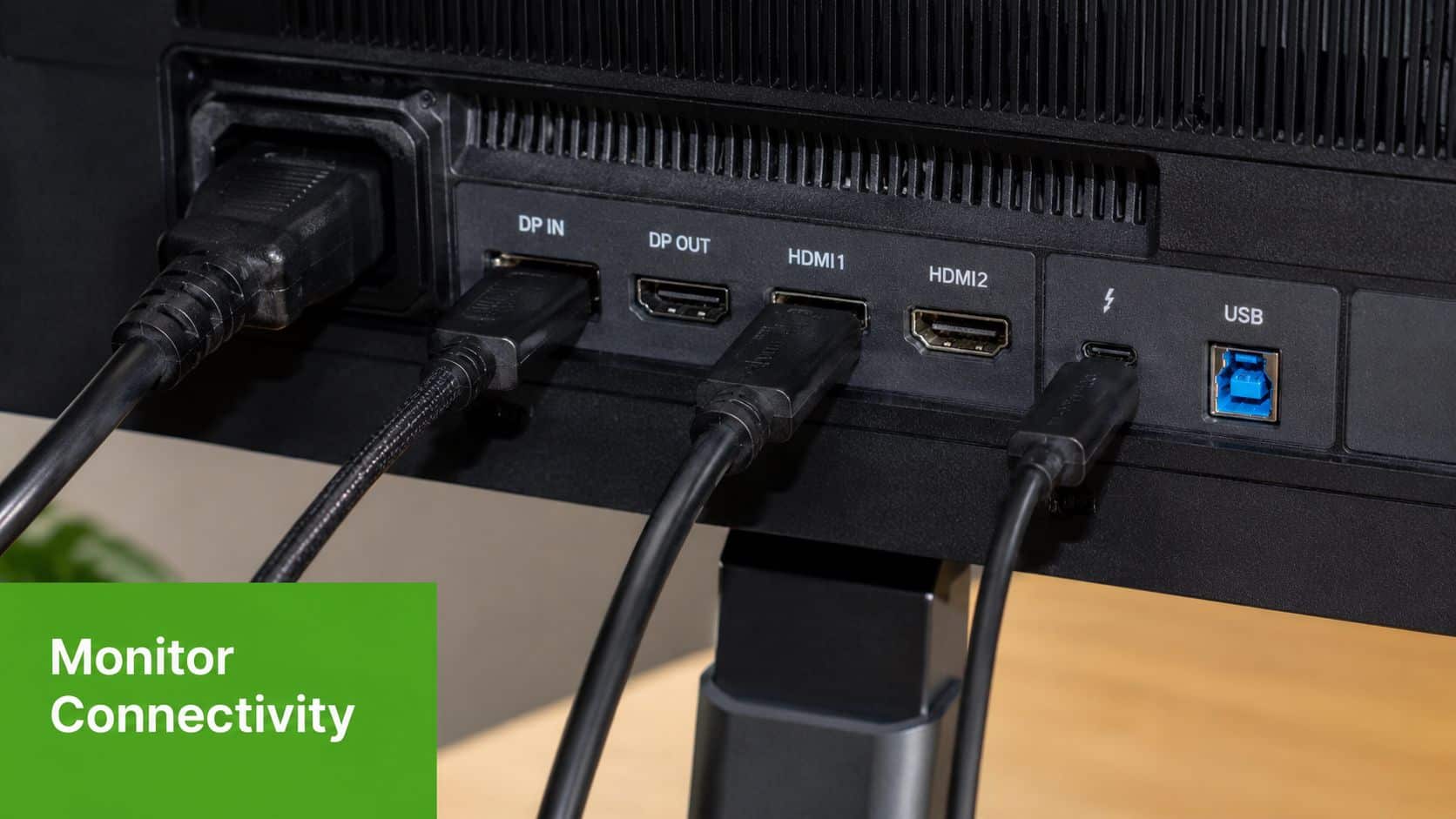 A close-up of a computer monitor's rear interface panel, showcasing various connectivity ports and attached cables.