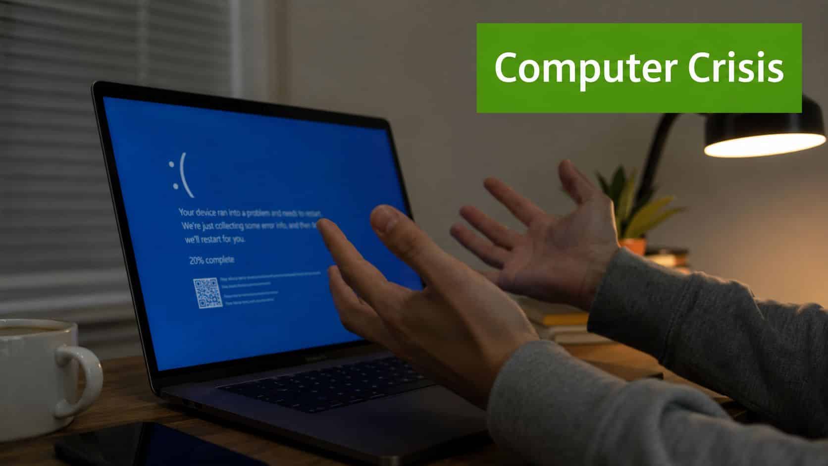 A person expresses frustration while sitting at a desk in front of a laptop computer screen error.