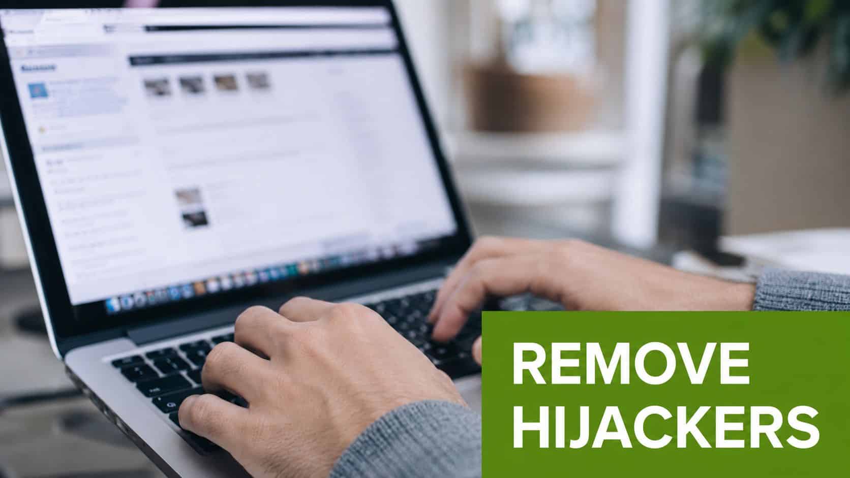 A close-up view of hands typing on a laptop keyboard to perform browser hijacker removal procedures.